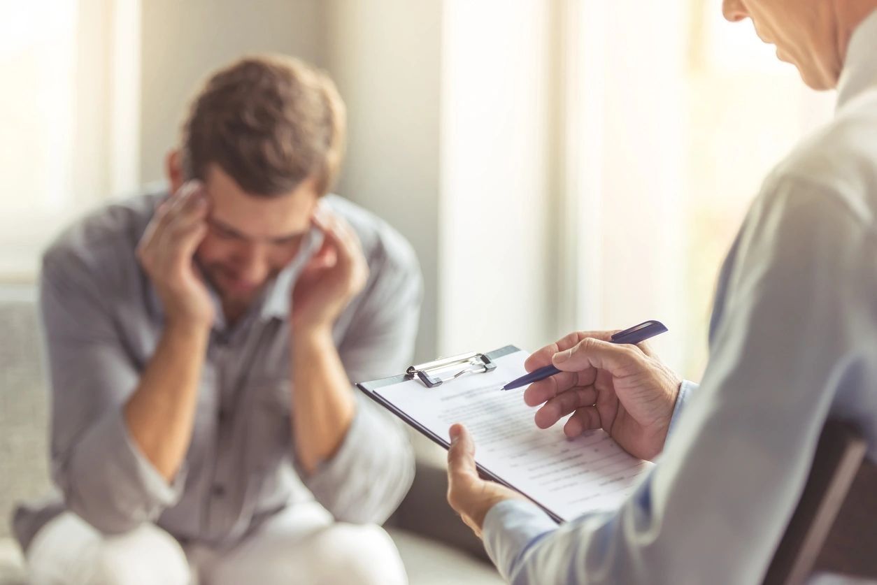 Male therapist taking notes during the session with a young man