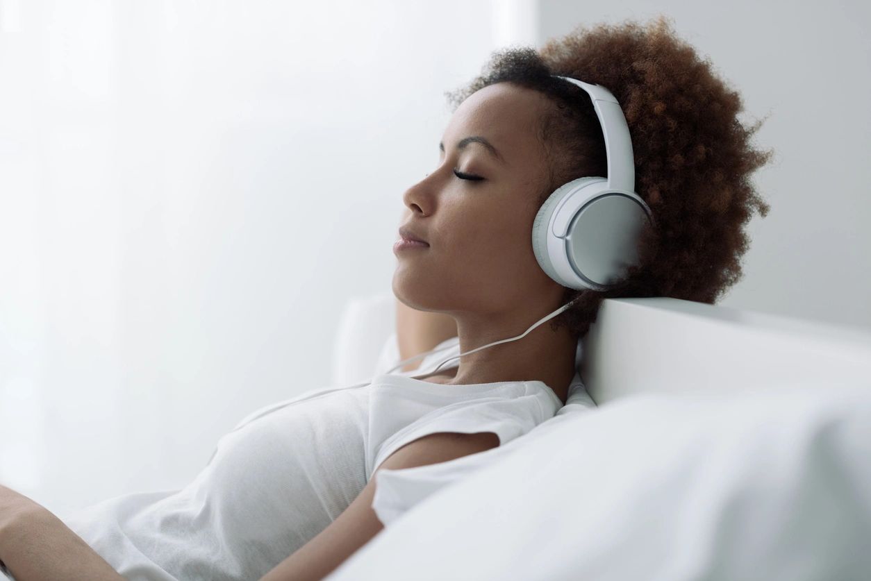 Person relaxing with headphones on a bed.